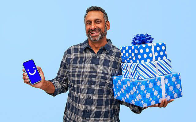 smiling man holding visible phone and presents