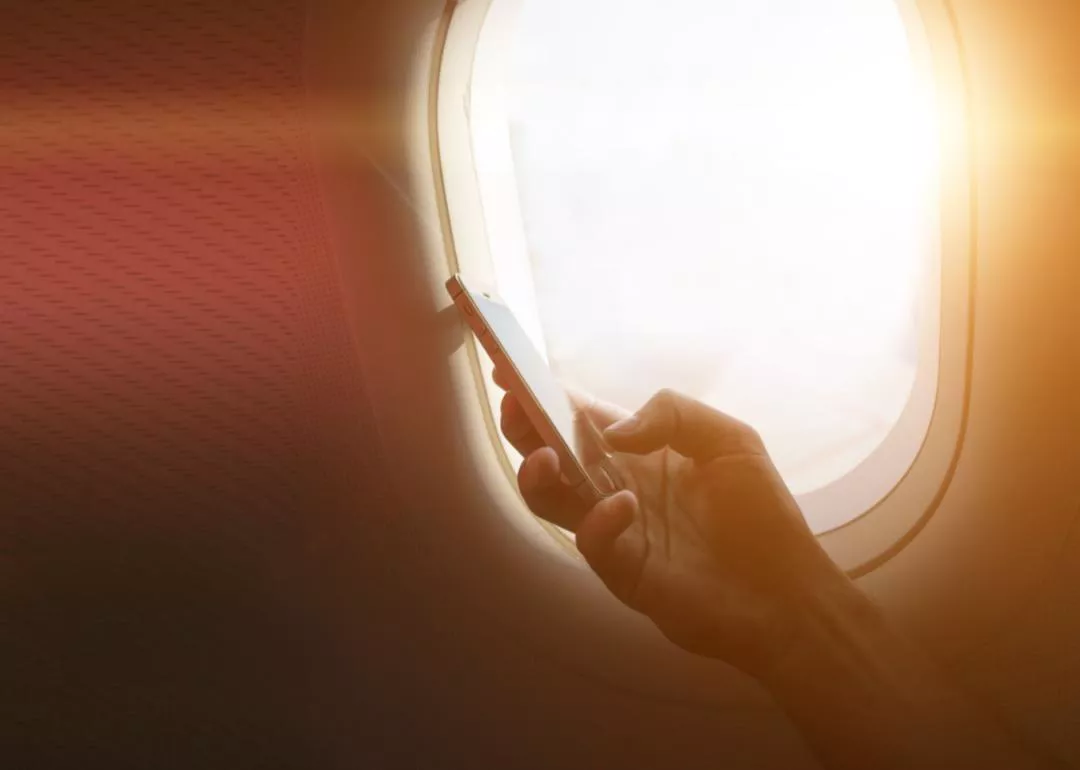 A person holding a phone next to an airplane window
