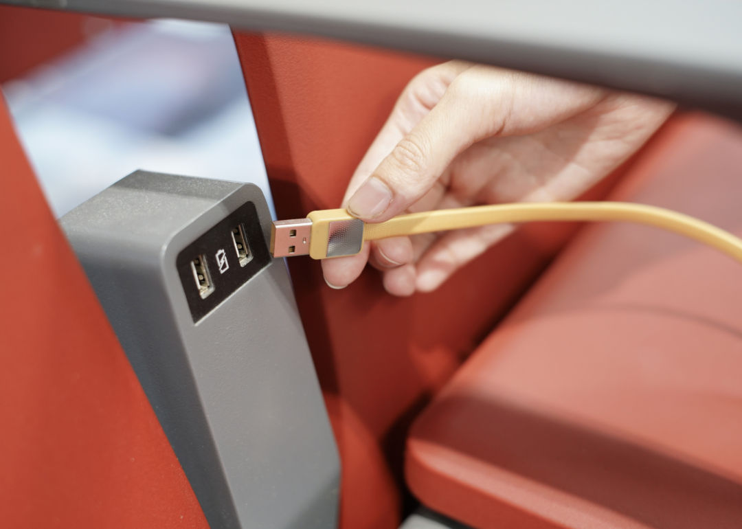 A person plugging in a phone charger between seats