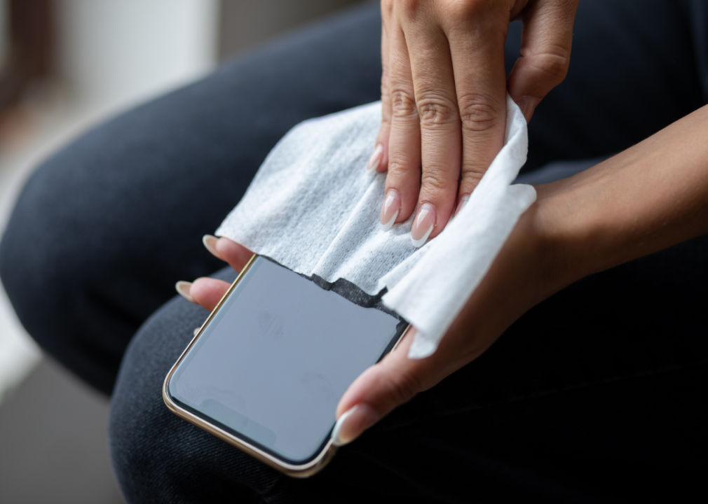 A person wiping a smartphone with a cloth
