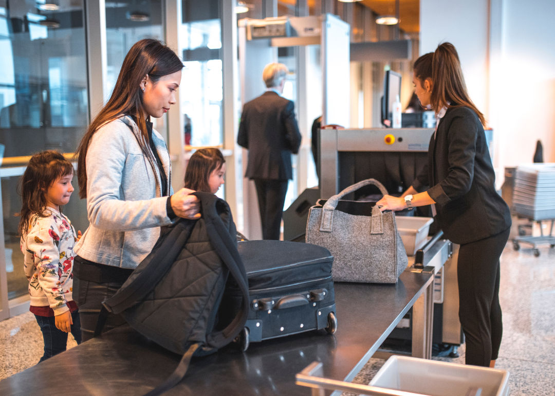 People putting luggage through a scanner at the airport.