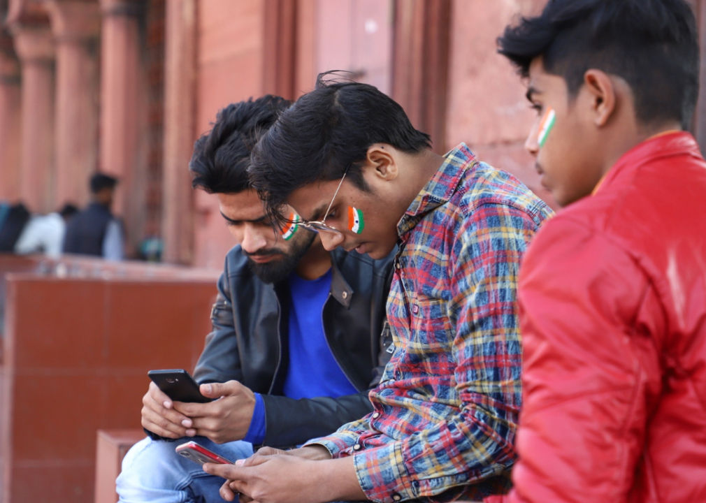 Young Indian men using their phones during a political event